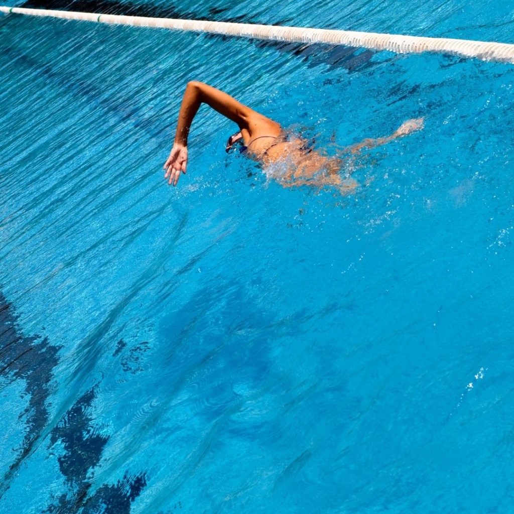 Mulher nadando em piscina raia 25 metros.